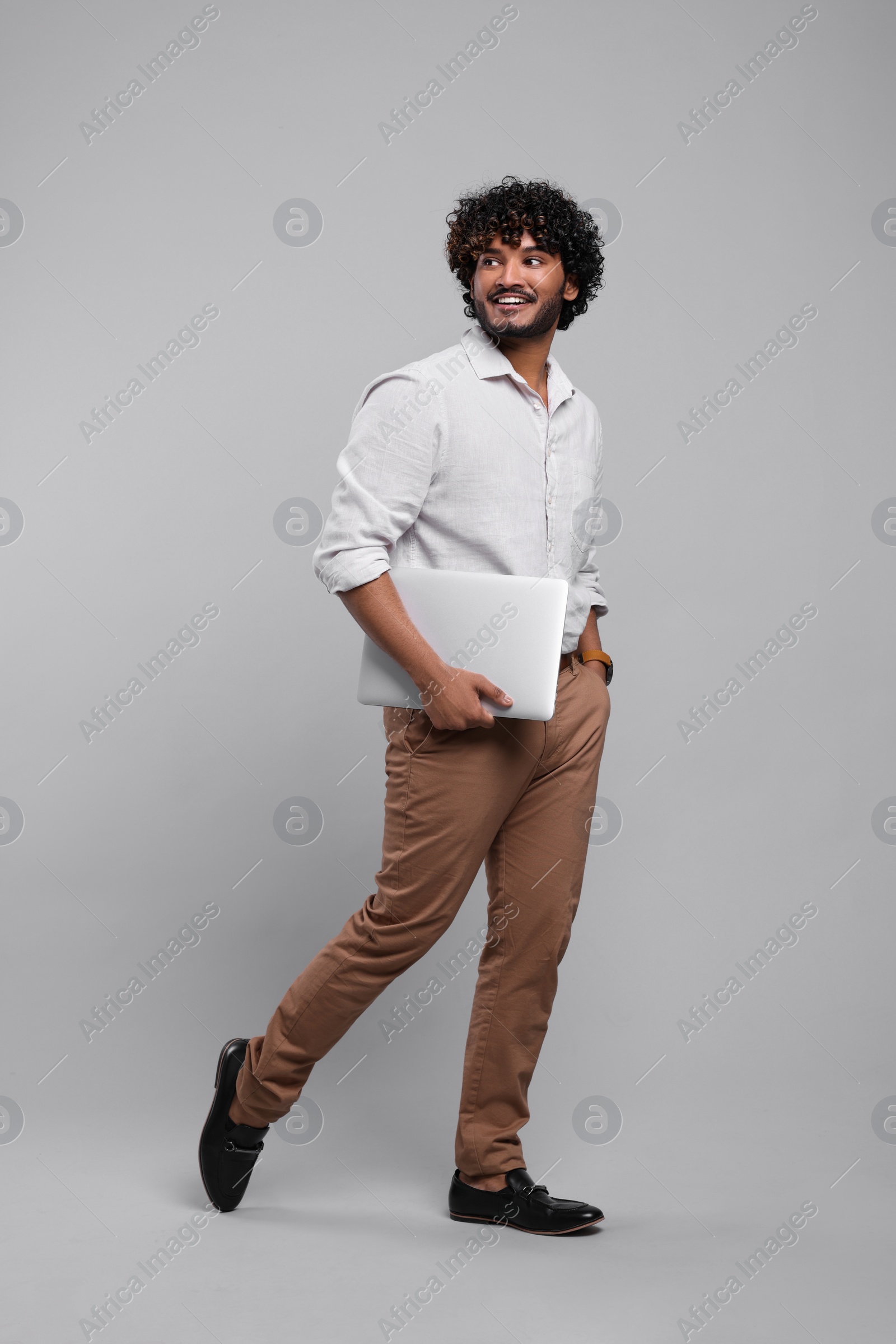 Photo of Smiling man with laptop on light grey background