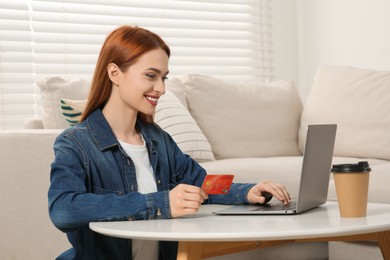 Happy woman with credit card using laptop for online shopping at home