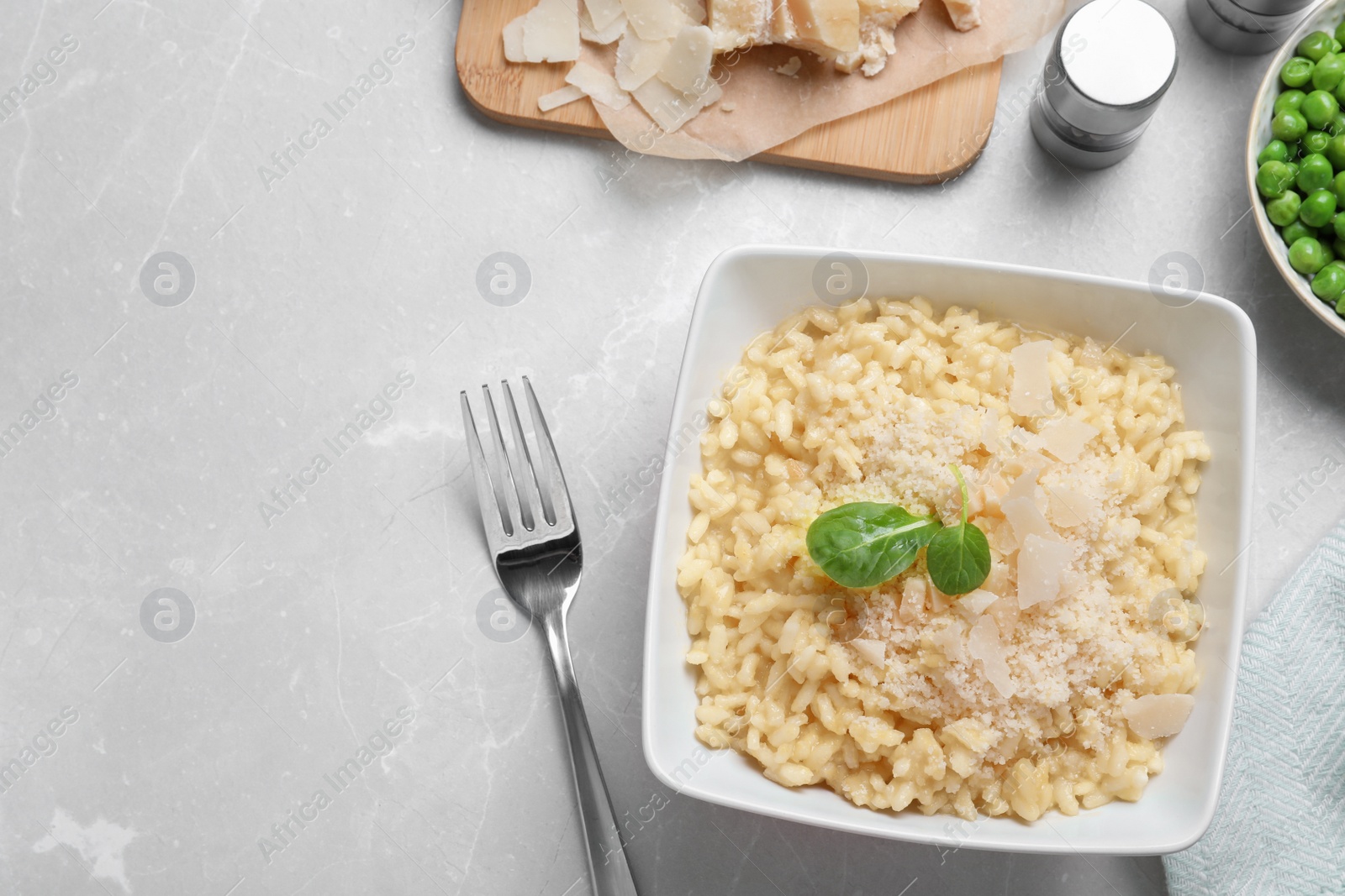 Photo of Delicious risotto with cheese on grey marble table, flat lay