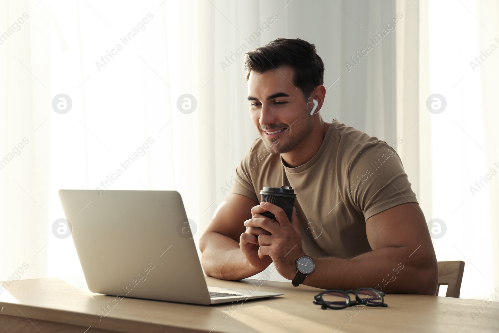 Photo of Portrait of young man with laptop at table indoors