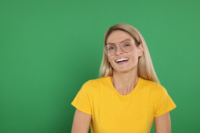 Photo of Portrait of smiling woman in stylish glasses on green background. Space for text