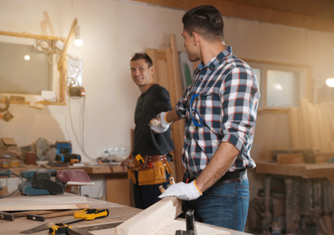 Photo of Carpenter giving tool to colleague in workshop
