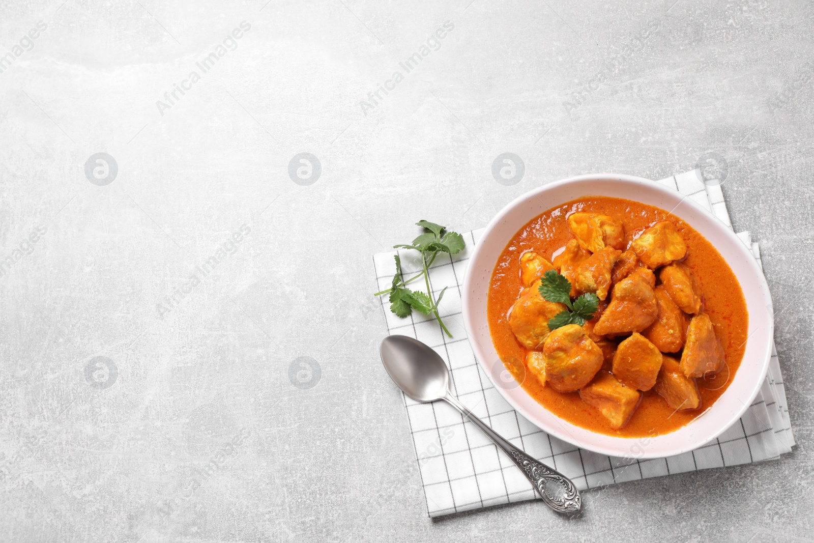 Photo of Bowl of delicious chicken curry on light grey table, top view. Space for text