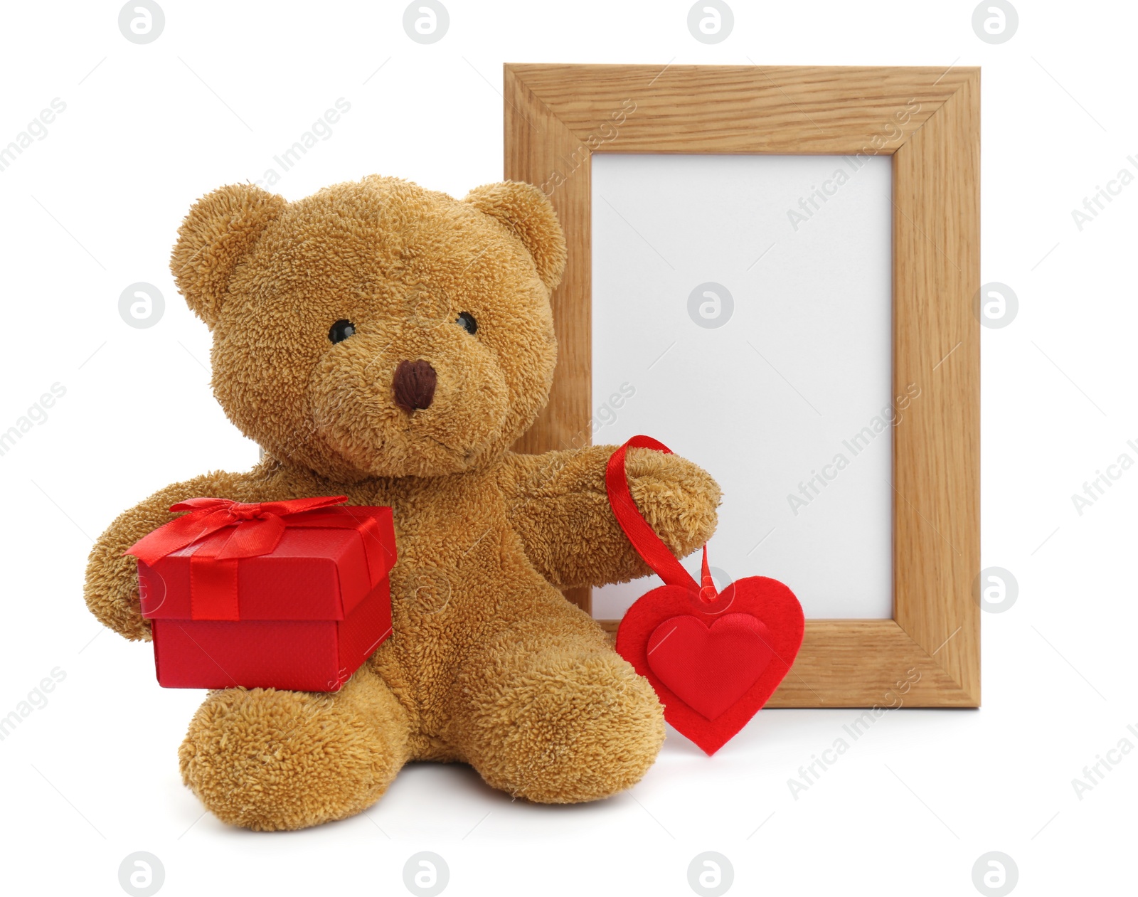 Photo of Cute teddy bear with red heart, gift box and frame on white background. Valentine's day celebration