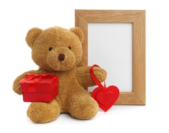 Photo of Cute teddy bear with red heart, gift box and frame on white background. Valentine's day celebration
