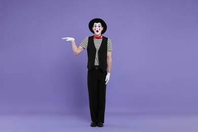 Mime artist making shocked face on purple background