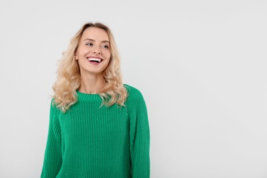 Photo of Happy woman in stylish warm sweater on white background. Space for text