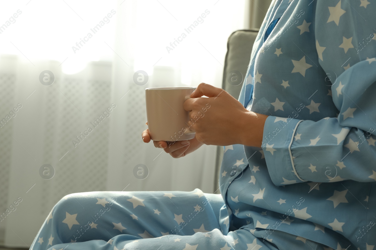 Photo of Woman in pajamas with cup at home, closeup