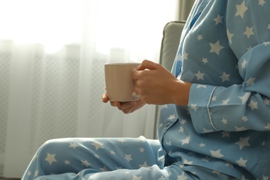 Photo of Woman in pajamas with cup at home, closeup