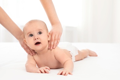 Mother and her cute child on bed indoors, space for text. Baby massage and exercises