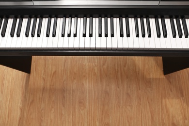 Photo of Modern piano with black and white keys over floor, top view. Space for text