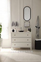 Stylish mat with pattern near chest of drawers in bathroom