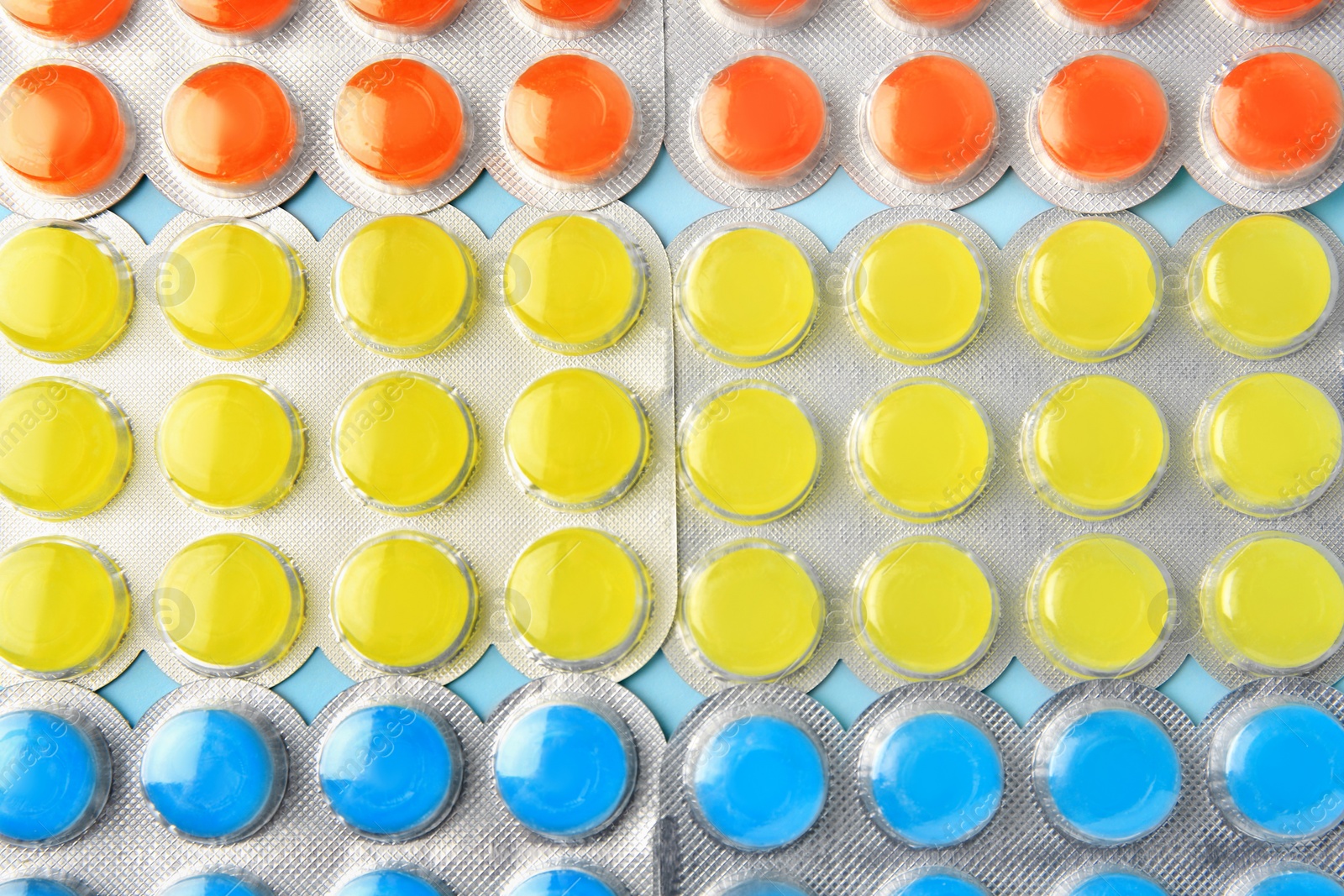 Photo of Blisters with cough drops on light blue background, flat lay