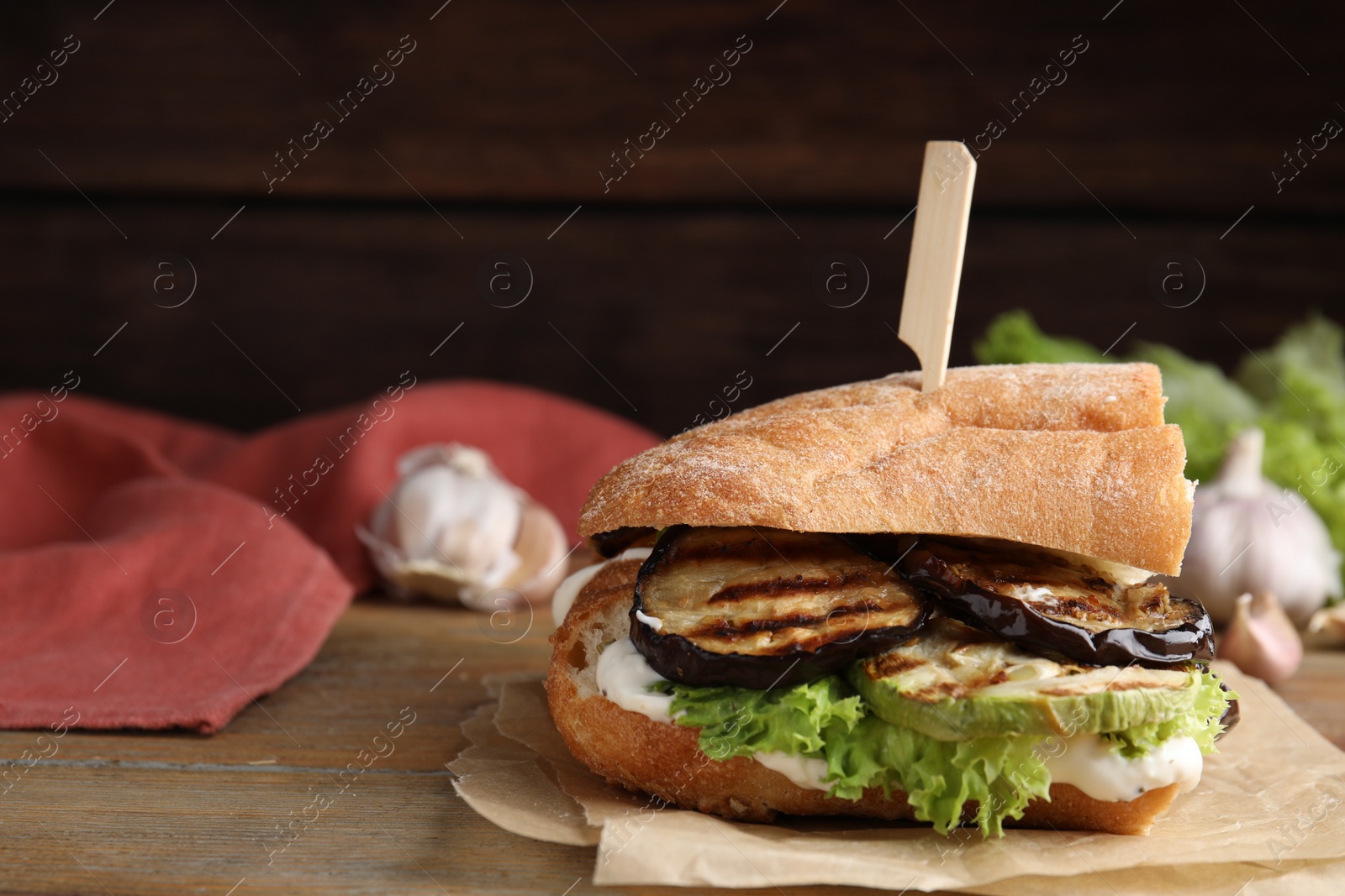 Photo of Delicious eggplant sandwich served on wooden table. Space for text