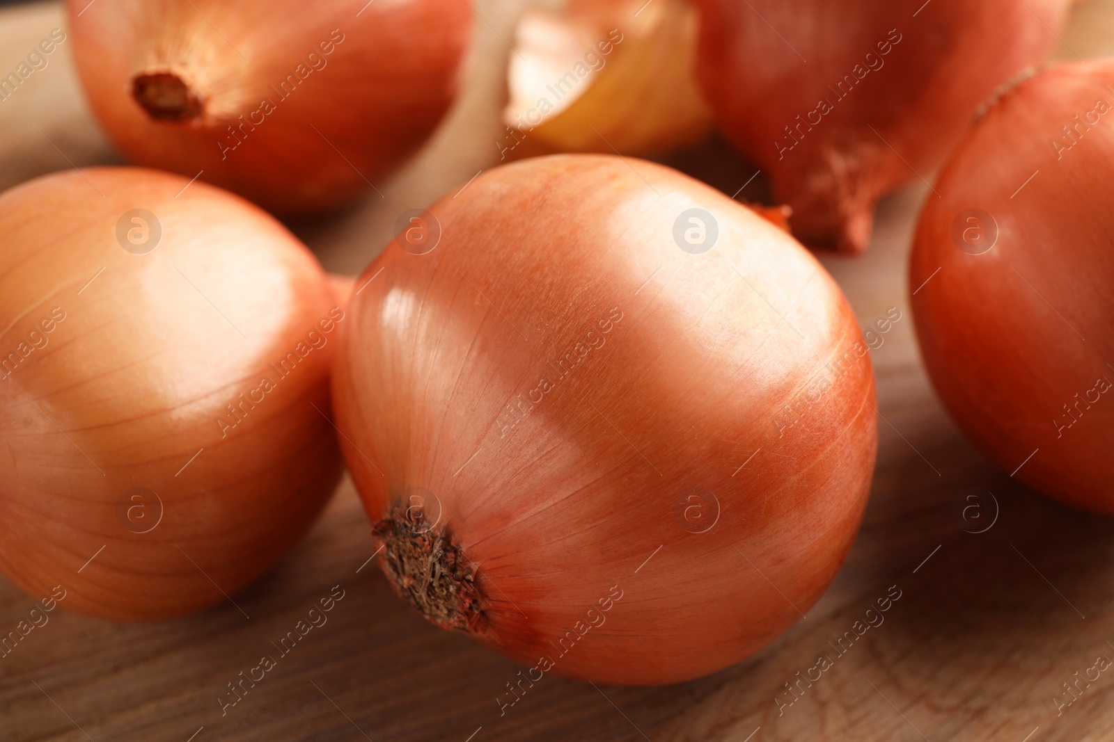 Photo of Many ripe onions on wooden table, closeup