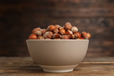 Photo of Ceramic bowl with acorns on wooden table. Cooking utensil