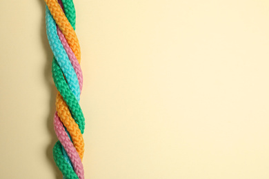Top view of twisted colorful ropes on beige background, space for text. Unity concept