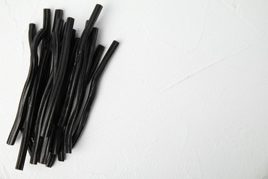 Photo of Tasty black liquorice candies on white table, top view. Space for text