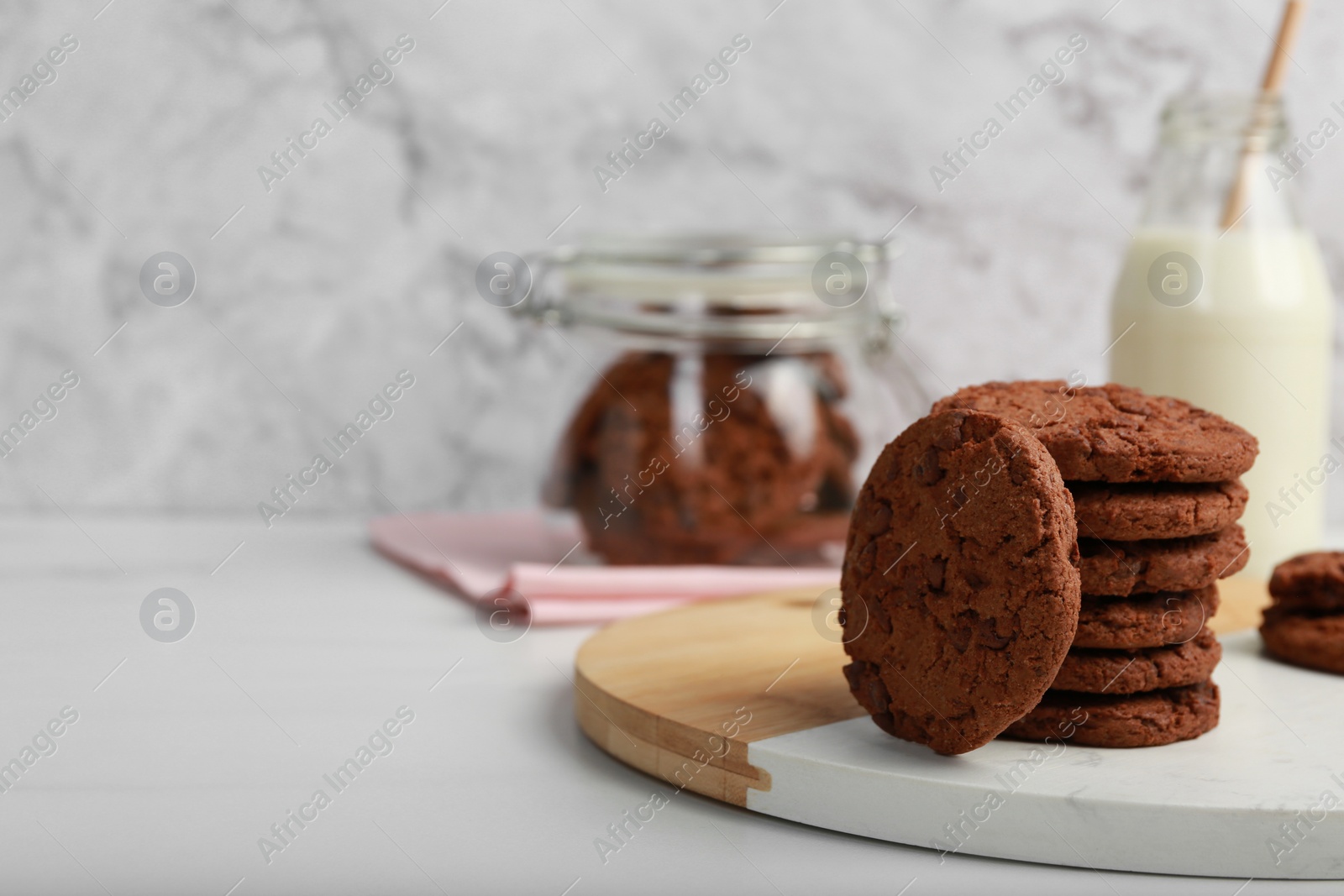 Photo of Board with tasty chocolate cookies on white table. Space for text