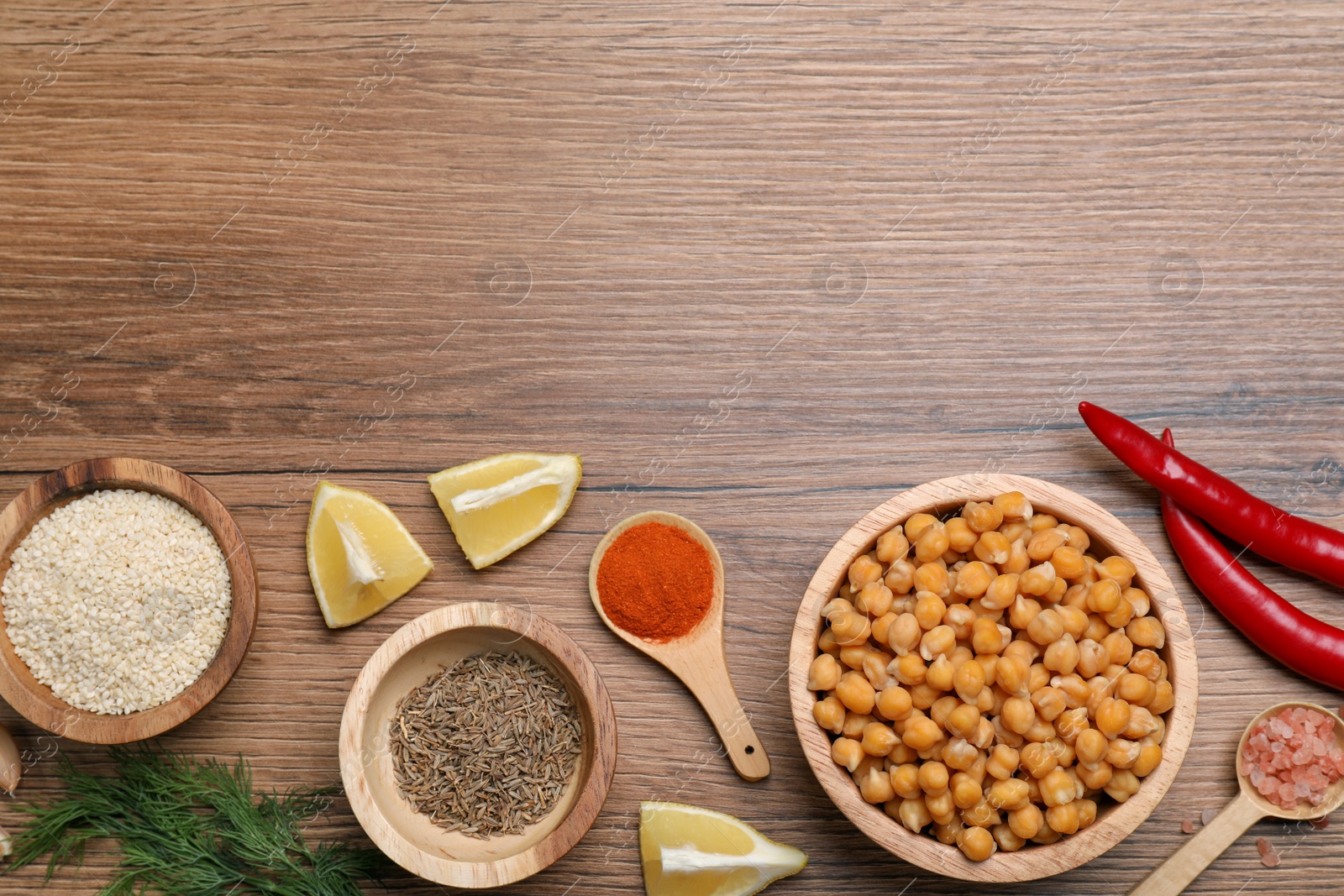 Photo of Delicious chickpeas and different products on wooden table, flat lay with space for text. Hummus ingredients