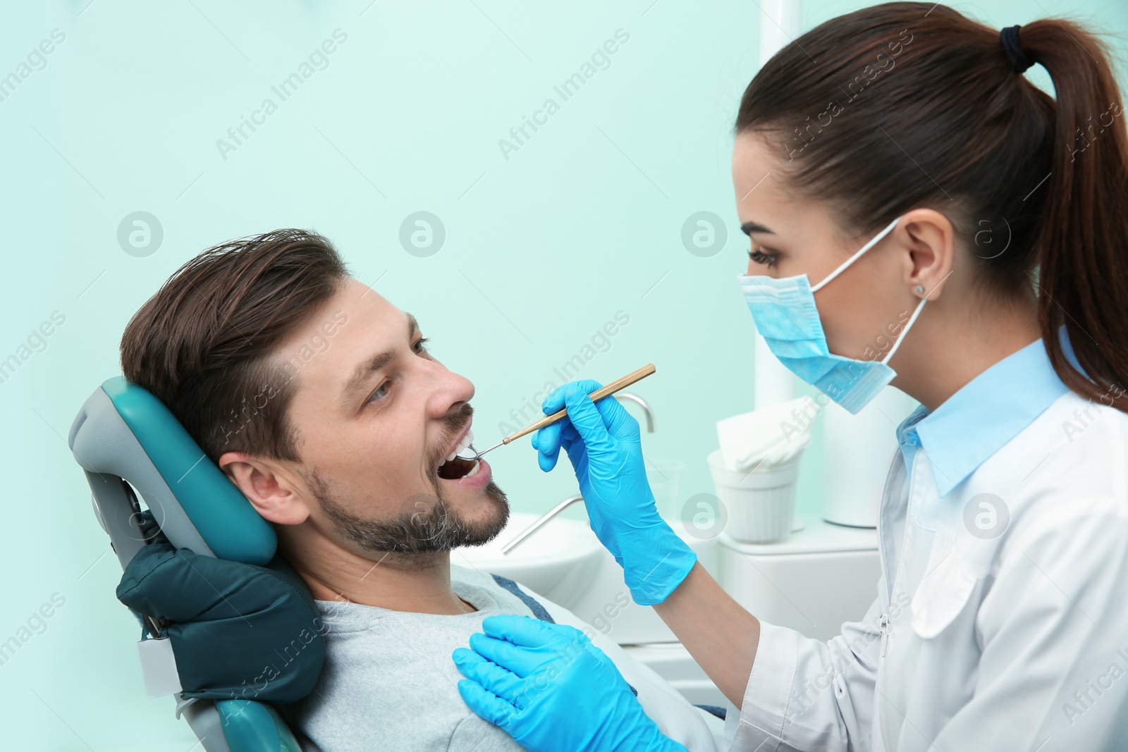 Photo of Professional dentist working with patient in modern clinic