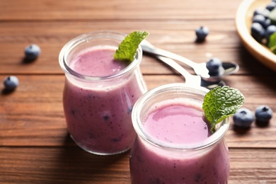 Tasty blueberry smoothie in jars and berries on wooden table