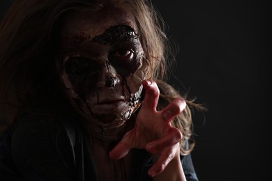 Photo of Scary zombie on dark background, closeup. Halloween monster