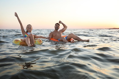 Happy young couple on inflatable rings in water