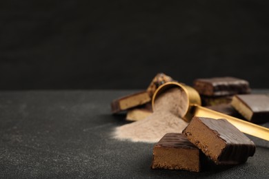 Different tasty energy bars and protein powder on grey table, space for text