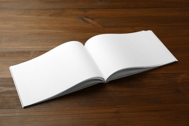 Photo of Open blank paper brochure on wooden table. Mockup for design