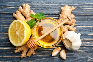Photo of Ginger and other natural cold remedies on blue wooden table, flat lay
