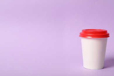 Takeaway paper coffee cup on violet background. Space for text