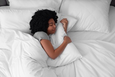 Beautiful young woman sleeping in soft bed, top view