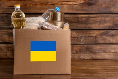 Humanitarian aid for Ukrainian refugees. Donation box with food on wooden background
