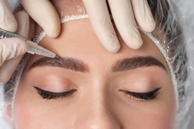 Photo of Young woman during procedure of permanent eyebrow makeup, closeup