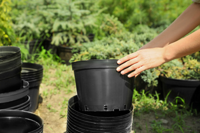 Photo of Woman with black pots for tree planting outdoors, closeup