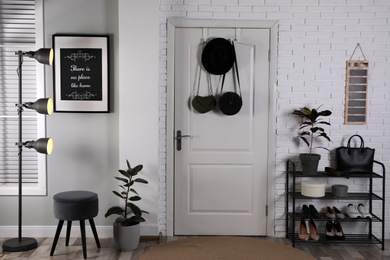 Hallway interior with stylish furniture, shoes and plants