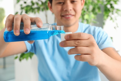 Man pouring mouthwash from bottle into cap, closeup. Teeth care