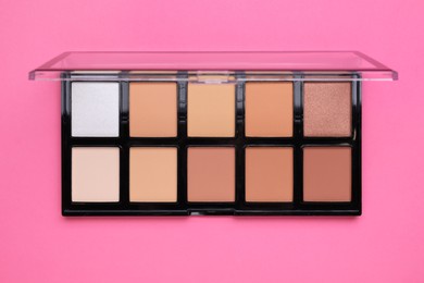 Photo of Colorful contouring palette on pink background, top view. Professional cosmetic product