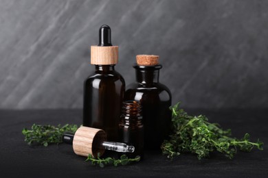 Photo of Natural thyme essential oil on black table
