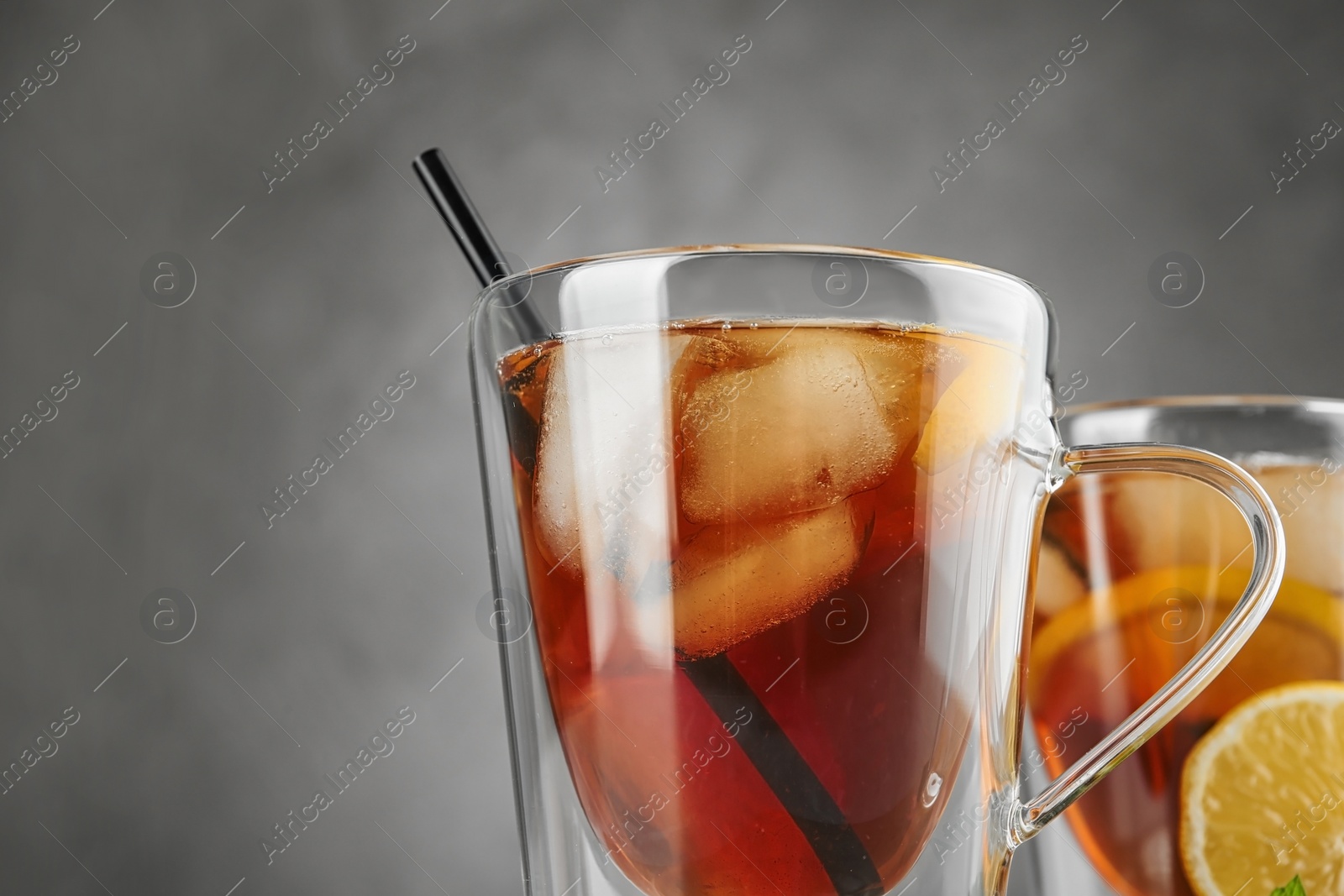 Photo of Cups of refreshing iced tea against grey background, closeup