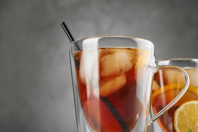 Photo of Cups of refreshing iced tea against grey background, closeup