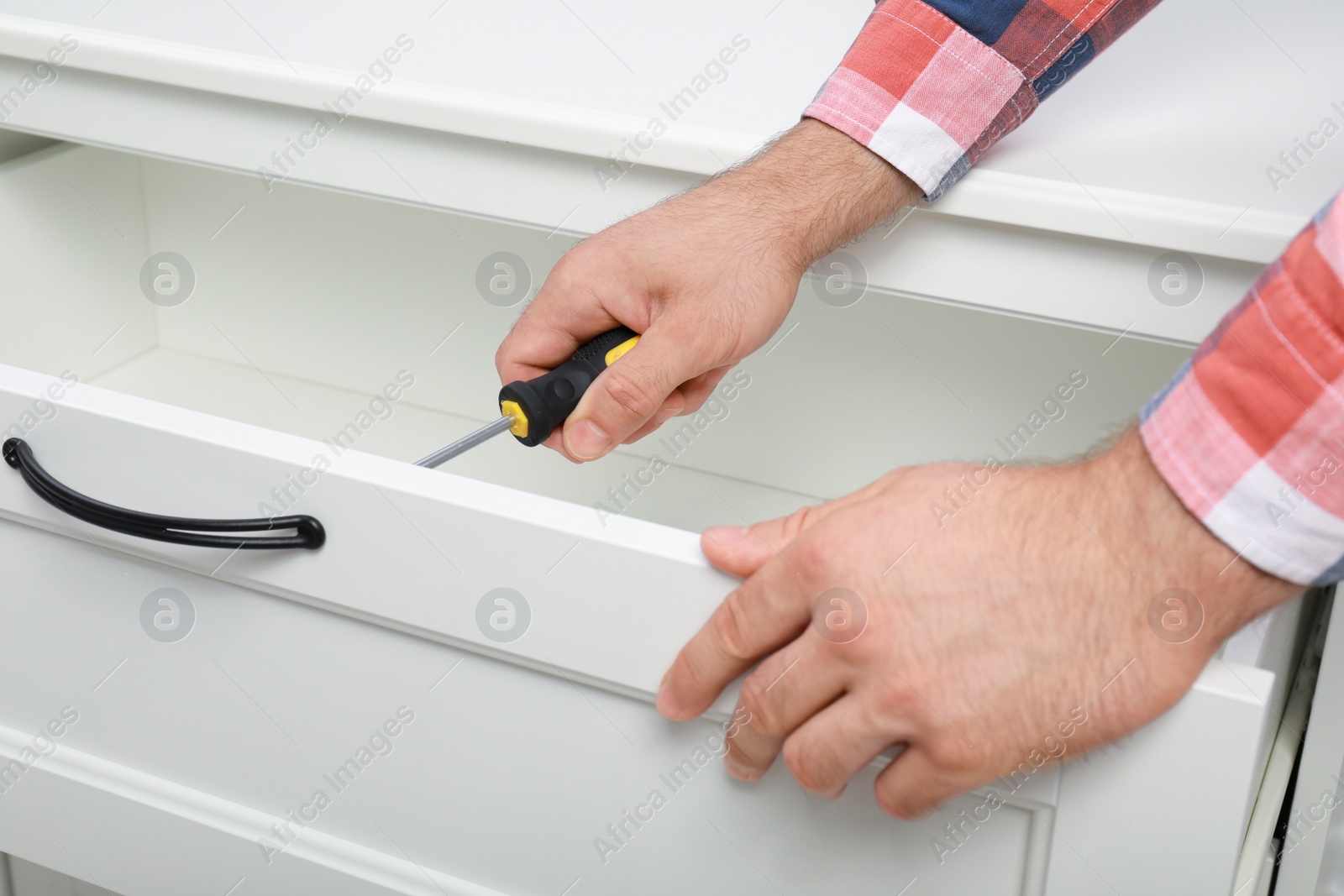 Photo of Man repairing chest of drawers indoors, closeup