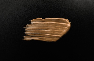 Photo of Golden paint brush stroke on black background