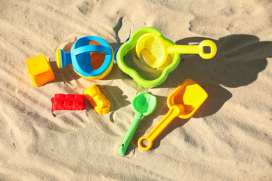 Different child plastic toys on sandy beach, flat lay