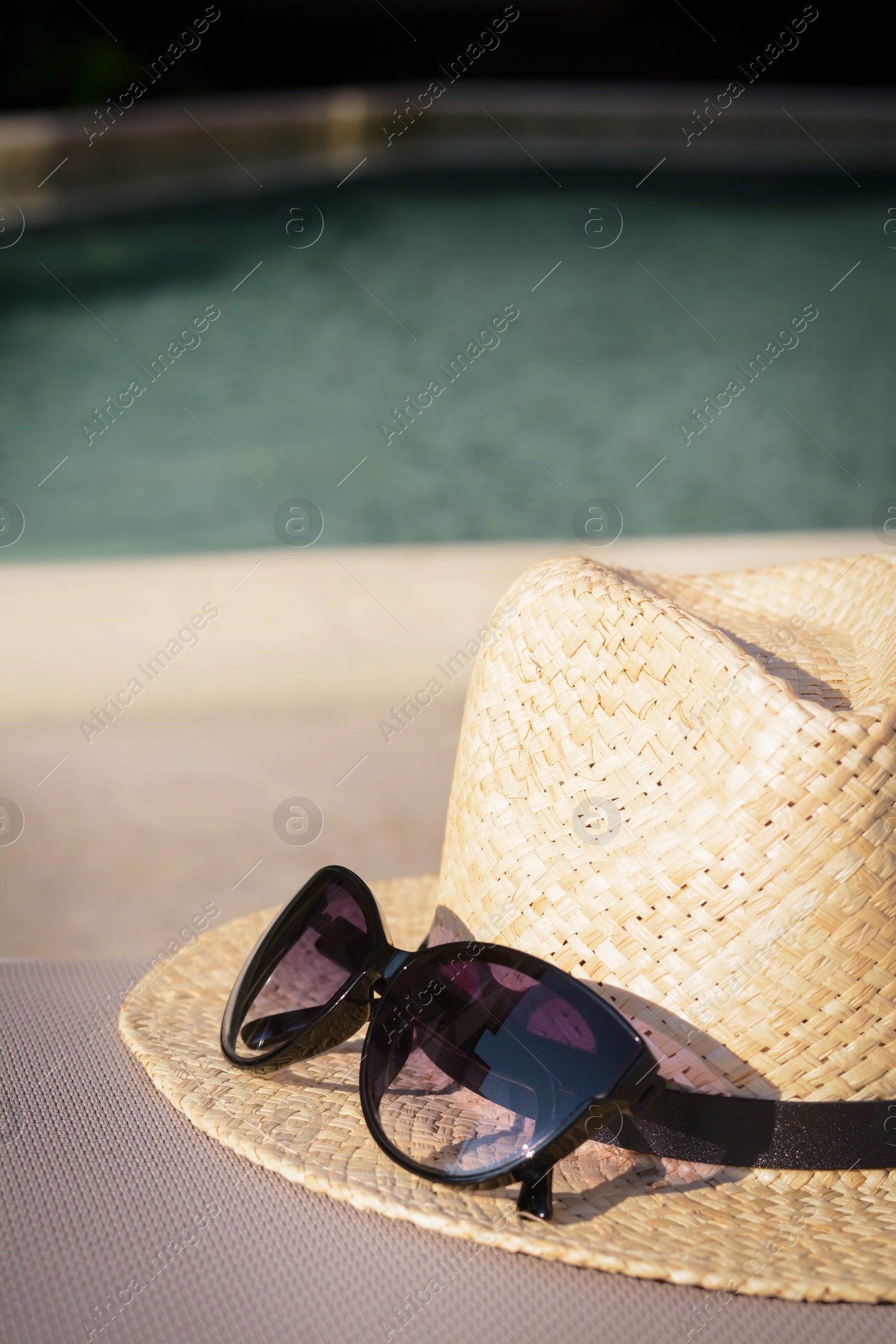Photo of Stylish hat and sunglasses near outdoor swimming pool