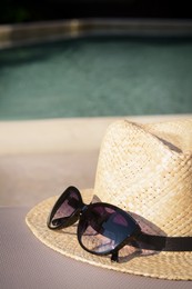 Photo of Stylish hat and sunglasses near outdoor swimming pool