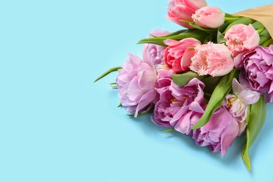 Beautiful bouquet of colorful tulip flowers on light blue background, space for text