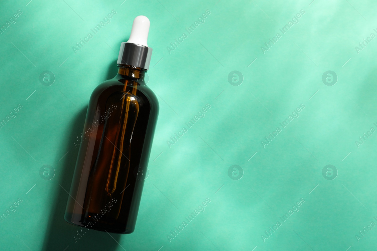 Photo of Bottle of hydrophilic oil on turquoise background, top view. Space for text