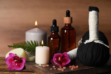Photo of Beautiful spa composition with different care products and burning candles on wooden table